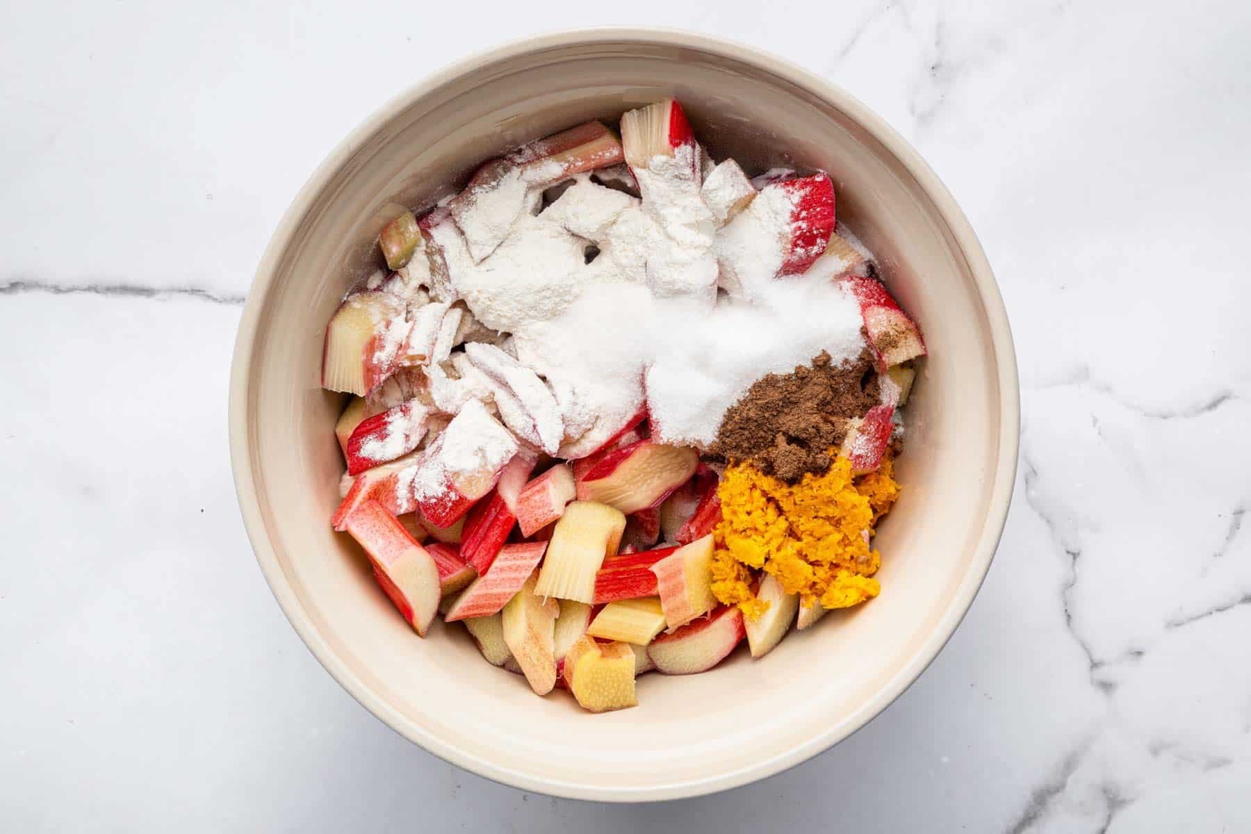 Big bowl with sliced fruit, orange zest and flour sprinkled on top.