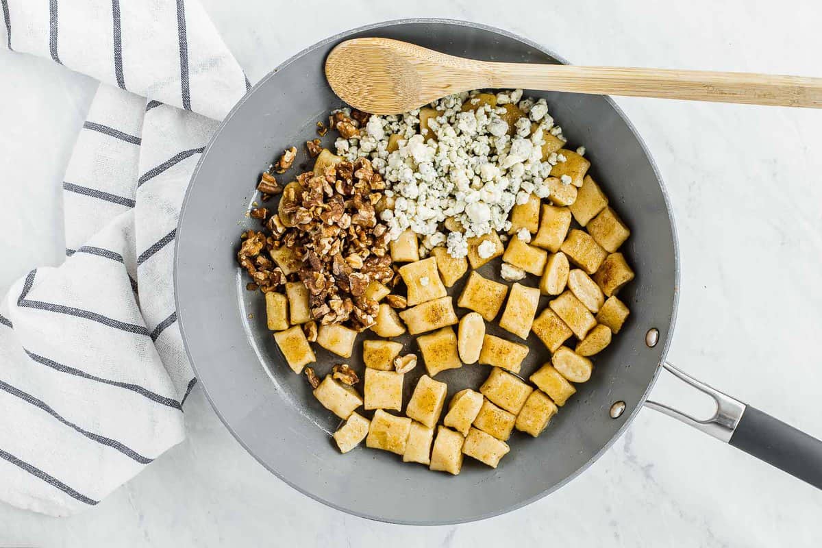 Gnocchi in skillet with walnuts and blue cheese crumbles.