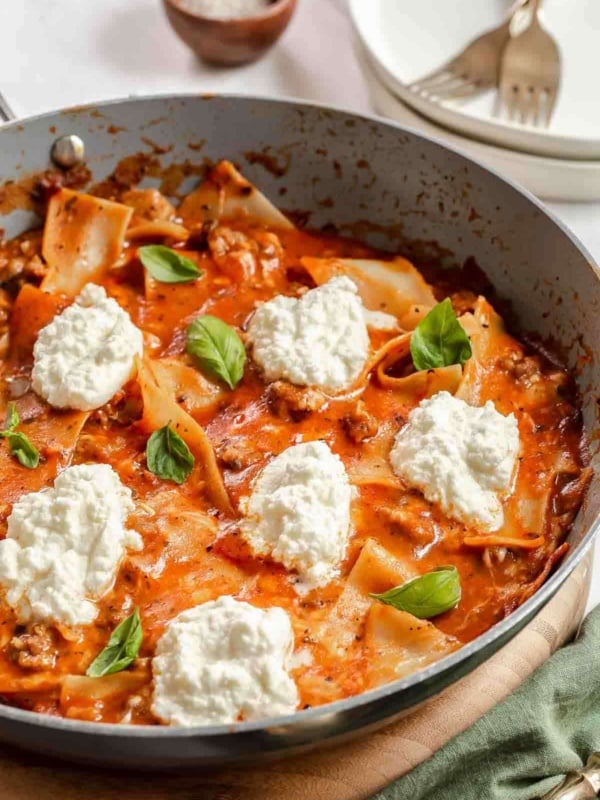 Skillet of lasagna with ricotta dollops.