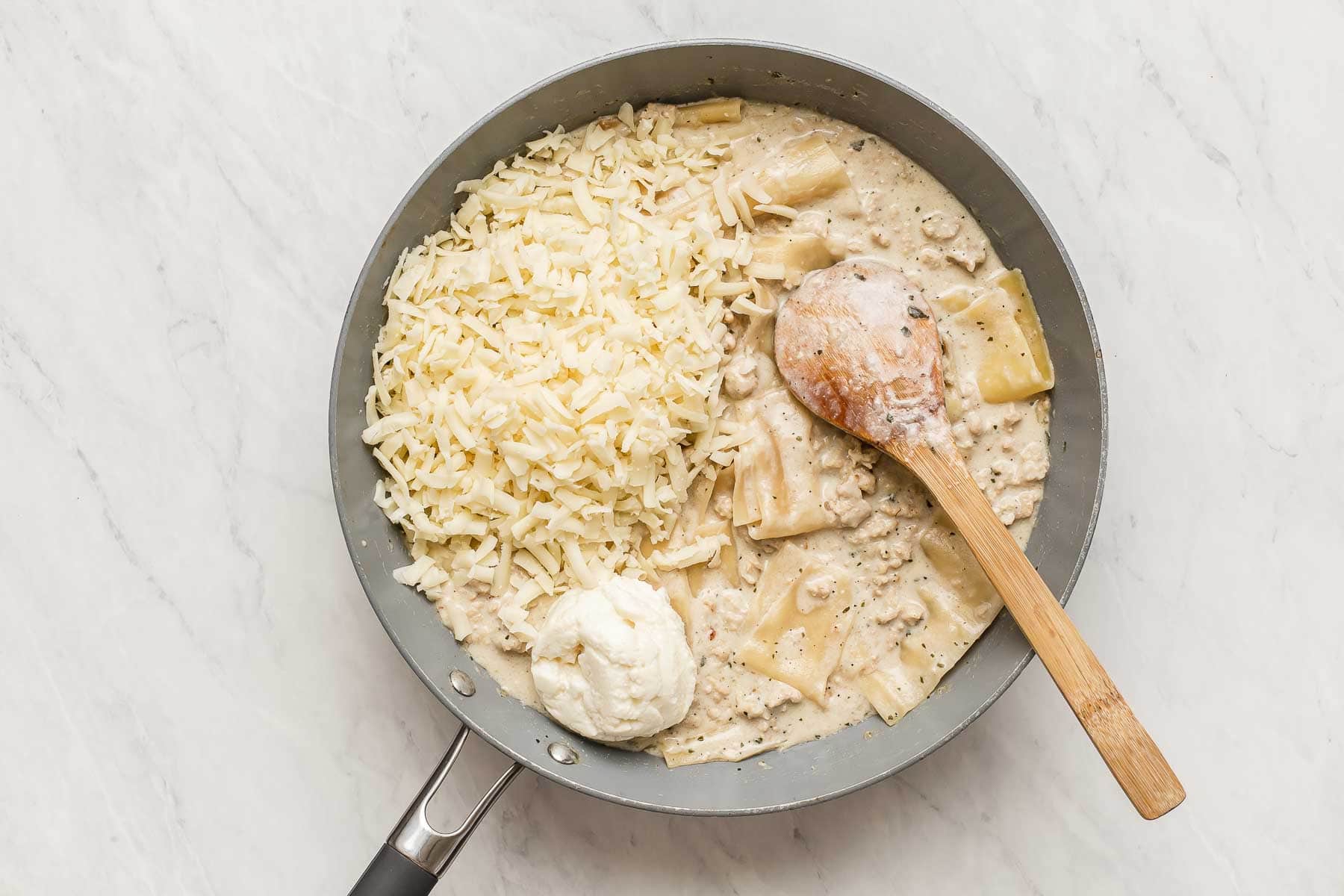 Adding cheese to a skillet lasagna.