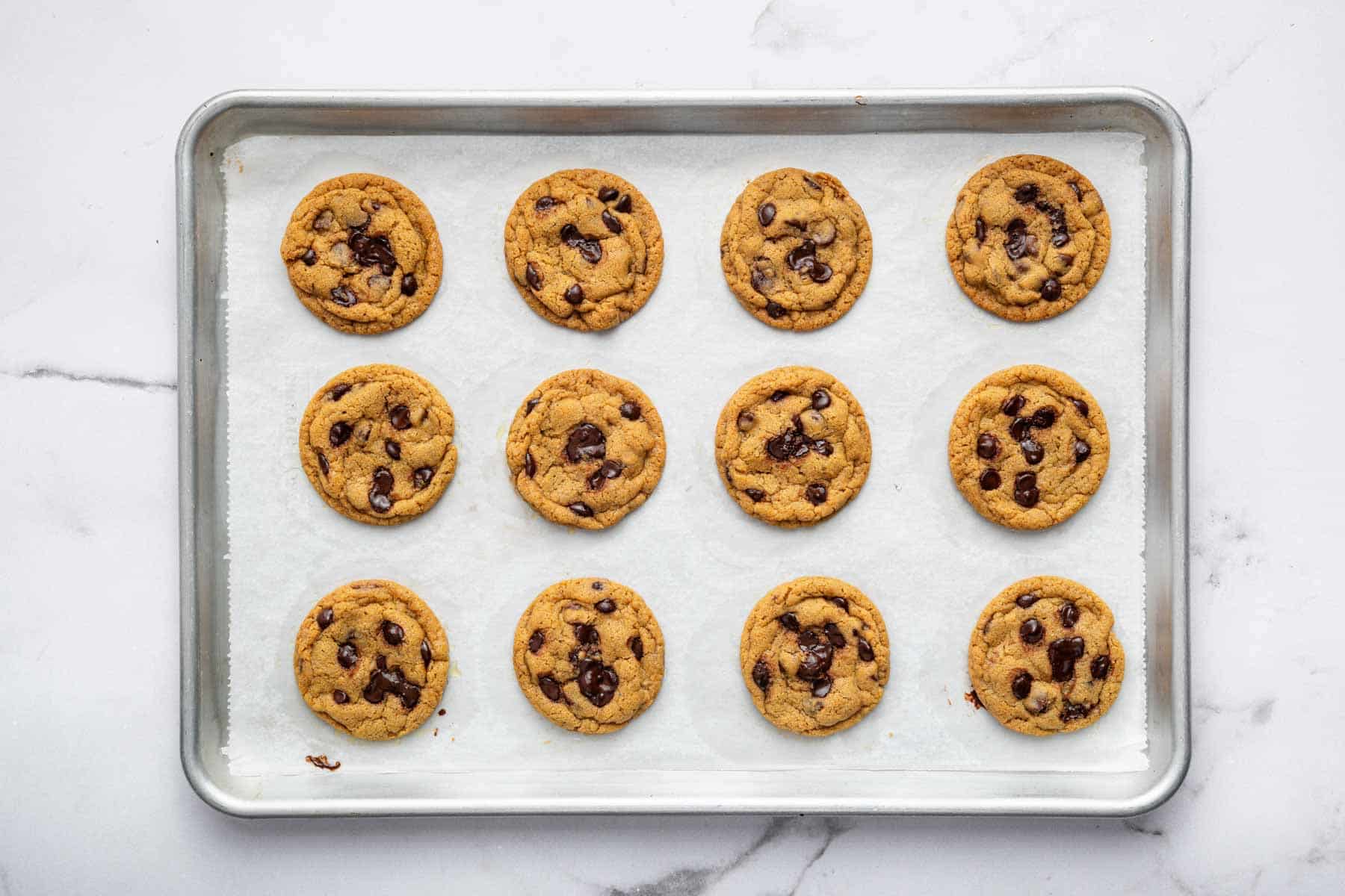 Twelve treats freshly baked on a sheet pan with parchment paper.