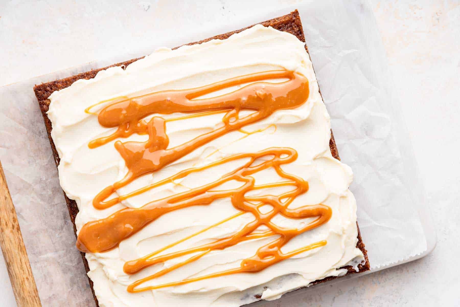 White frosting swirled with caramel on a square cake.