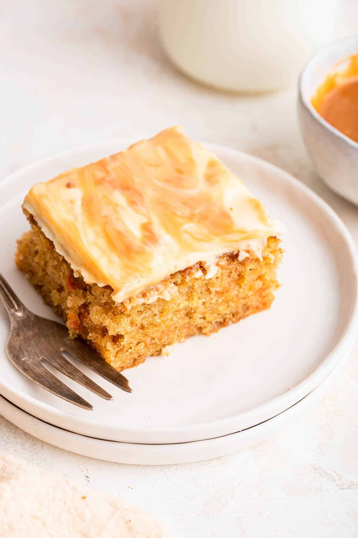 Slice of carrot cake on white plate with fork on side.