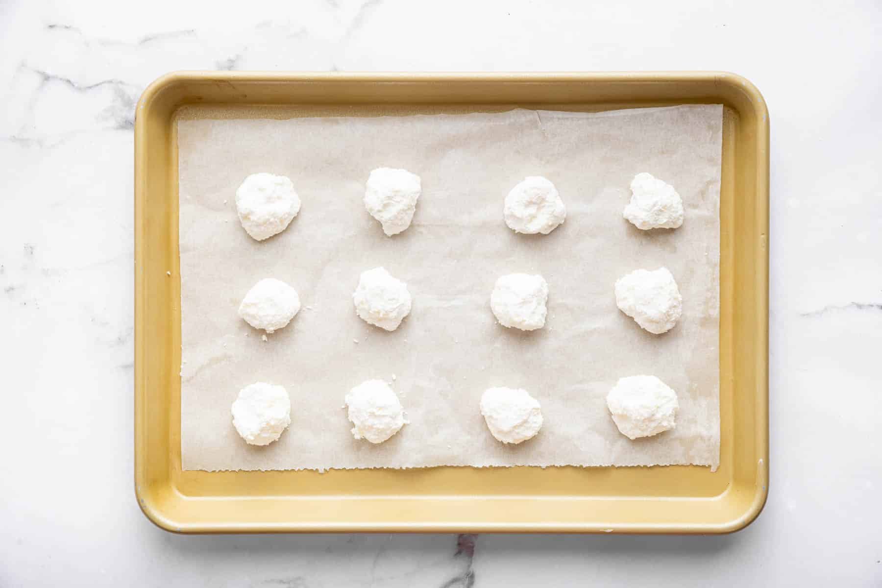 Twelve white balls of dough on baking sheet.