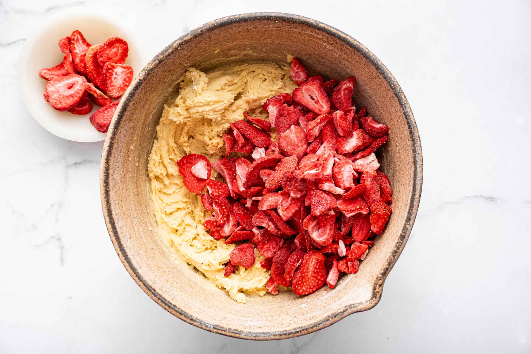 Bright red fruit in a bowl of yellow batter.