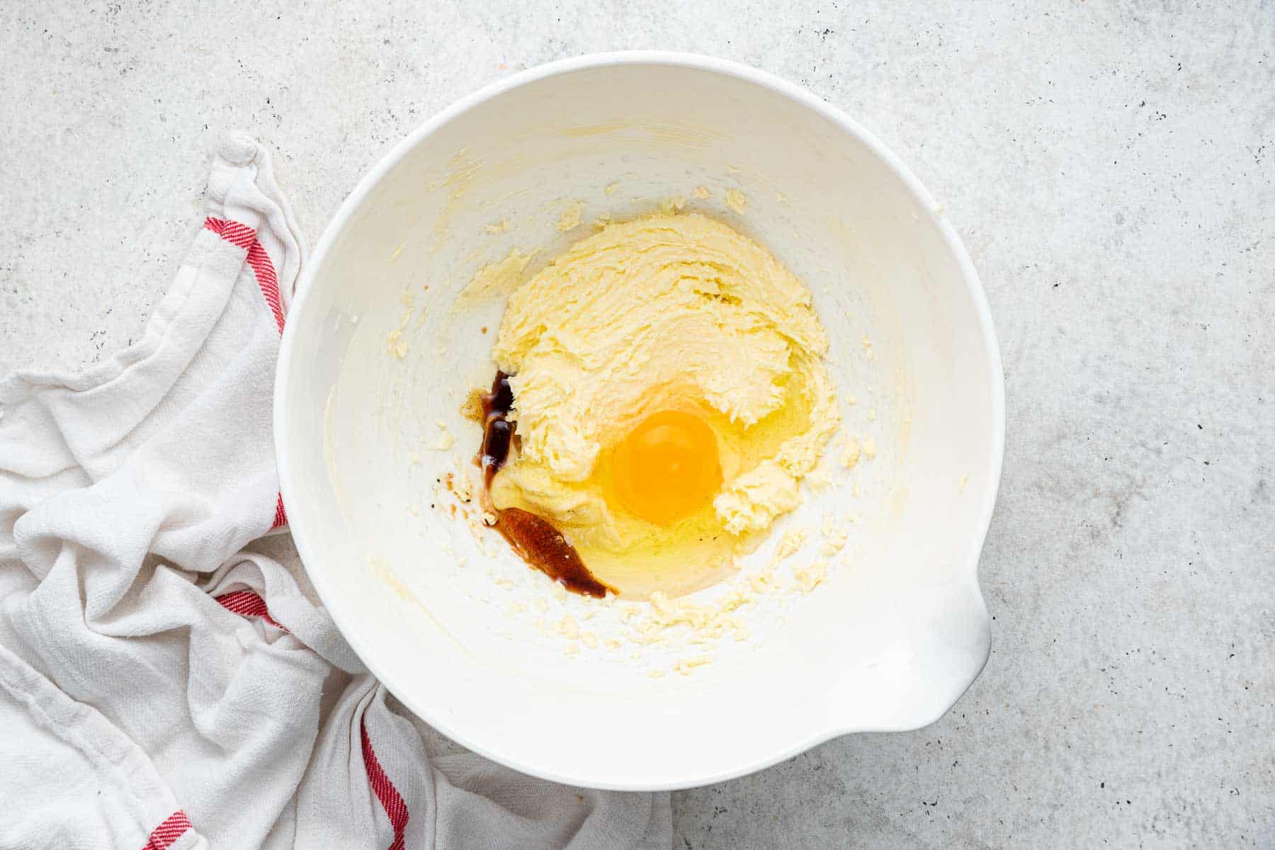 Yellow batter with whole cracked egg, vanilla extract and almond extract on top.