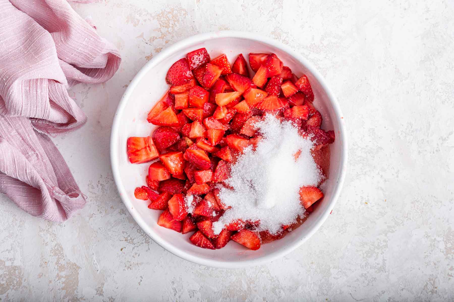 Bowl of diced fresh strawberries with sugar sprinkled on top.