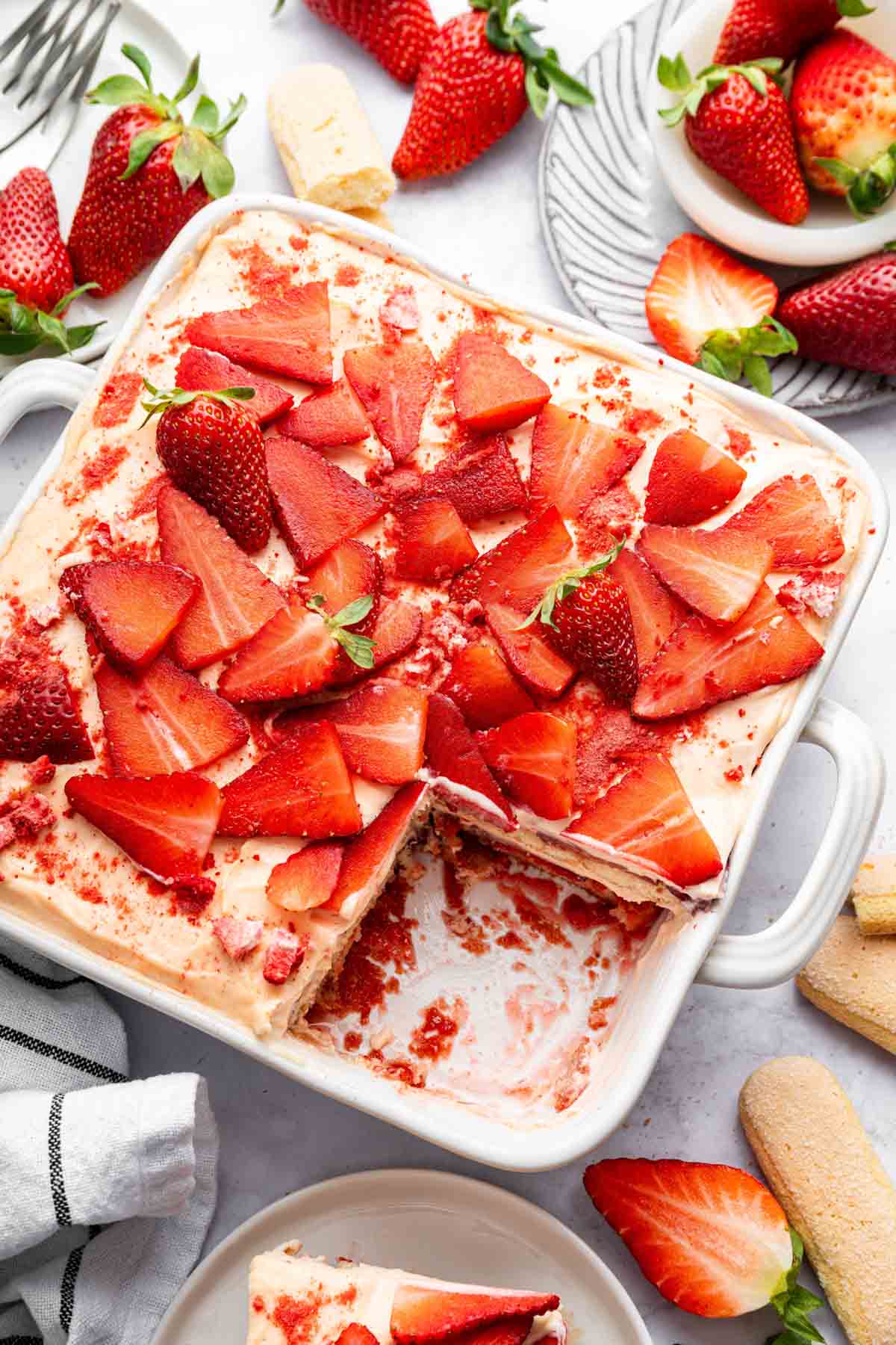 Finished strawberry tiramisu in square dish with one slice missing.