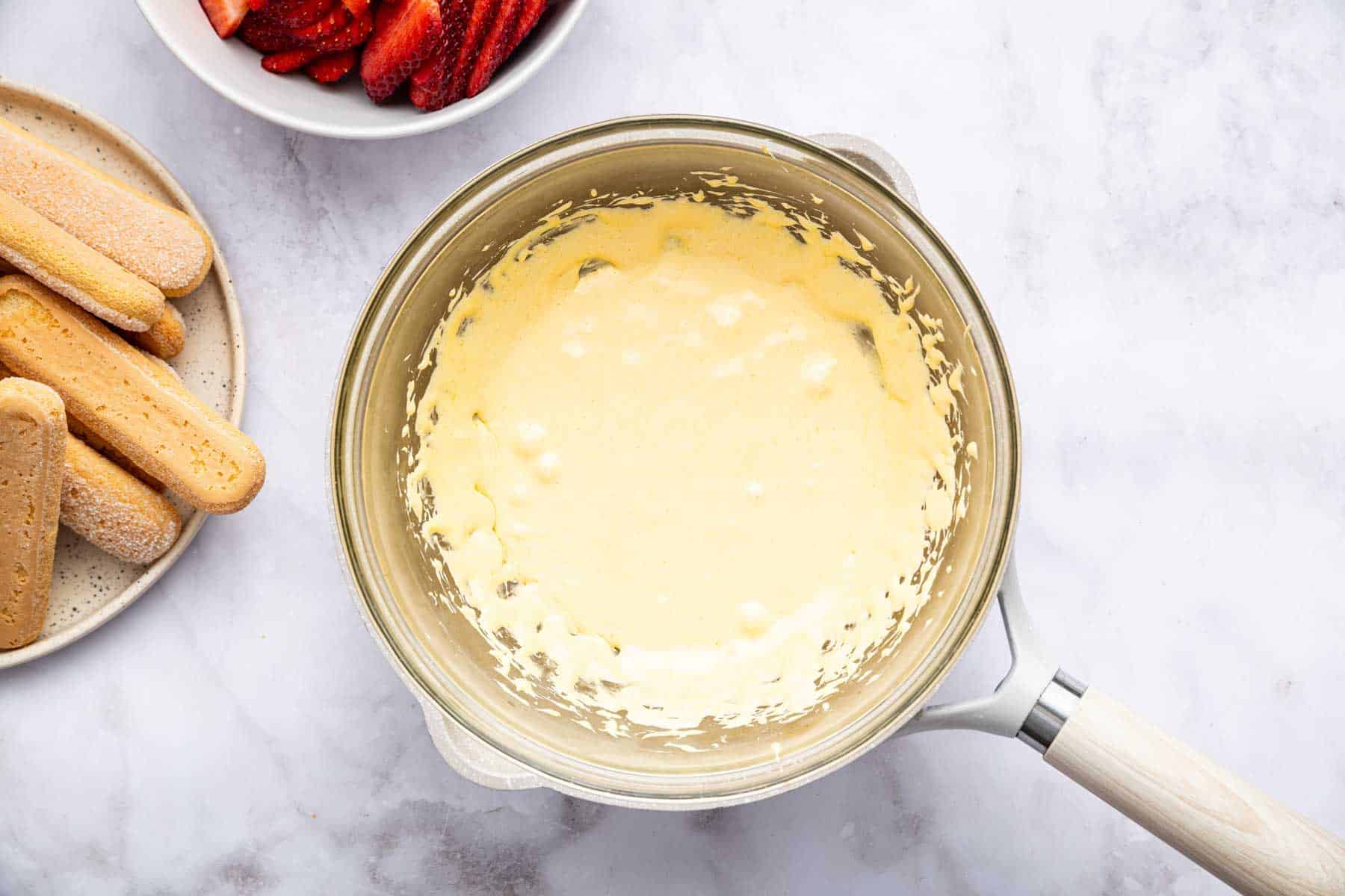 Yellow cooked zabaglione in a small sauce pan.