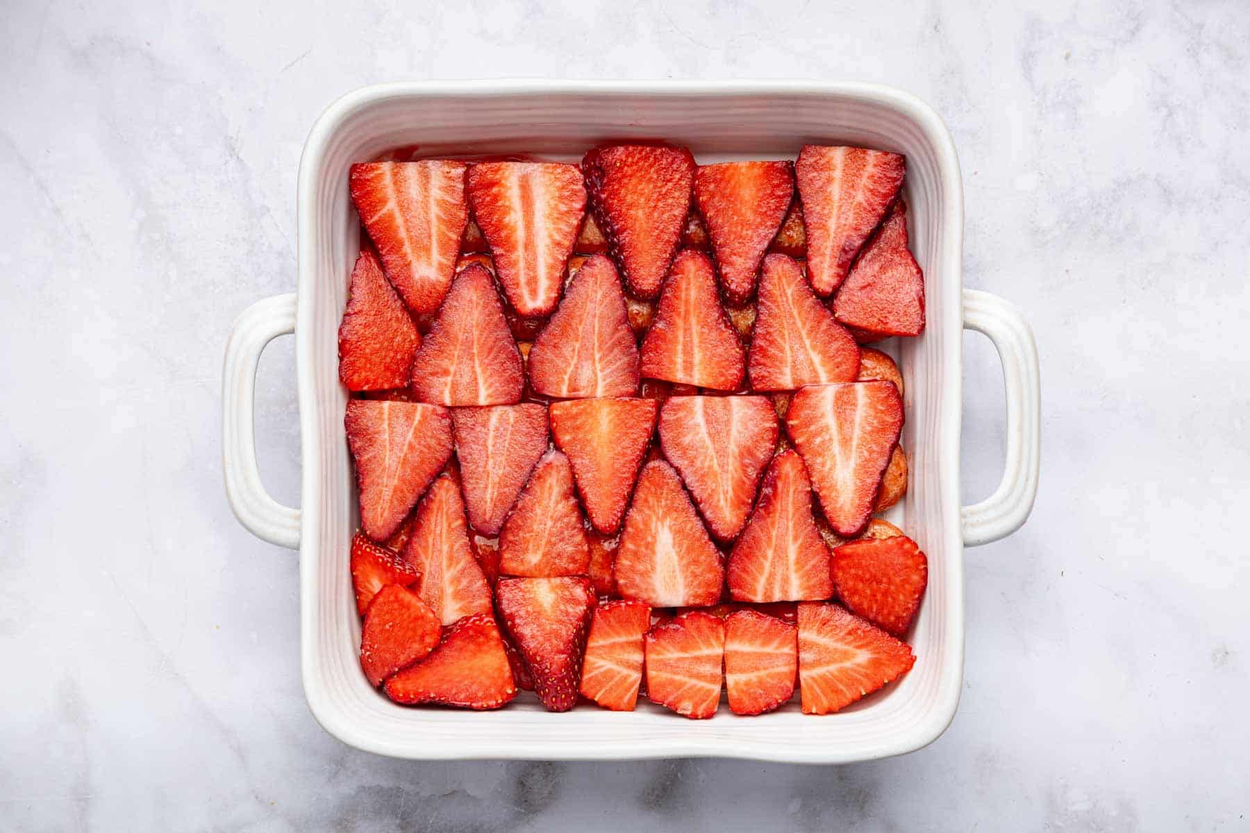 Thinly sliced fruit arranged in a single layer in a square dish.