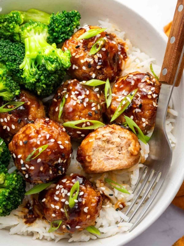 Bowl of teriyaki chicken meatballs over rice with broccoli on the side.