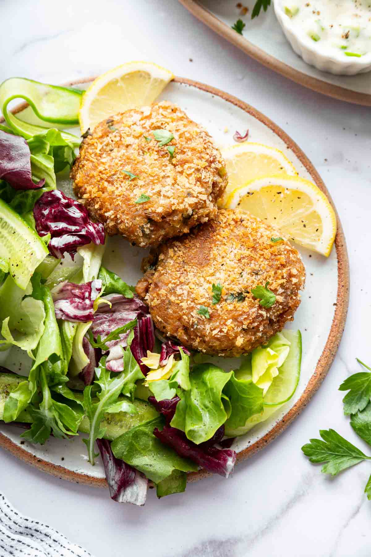 Tuna patties on a plate with mixed greens salad.