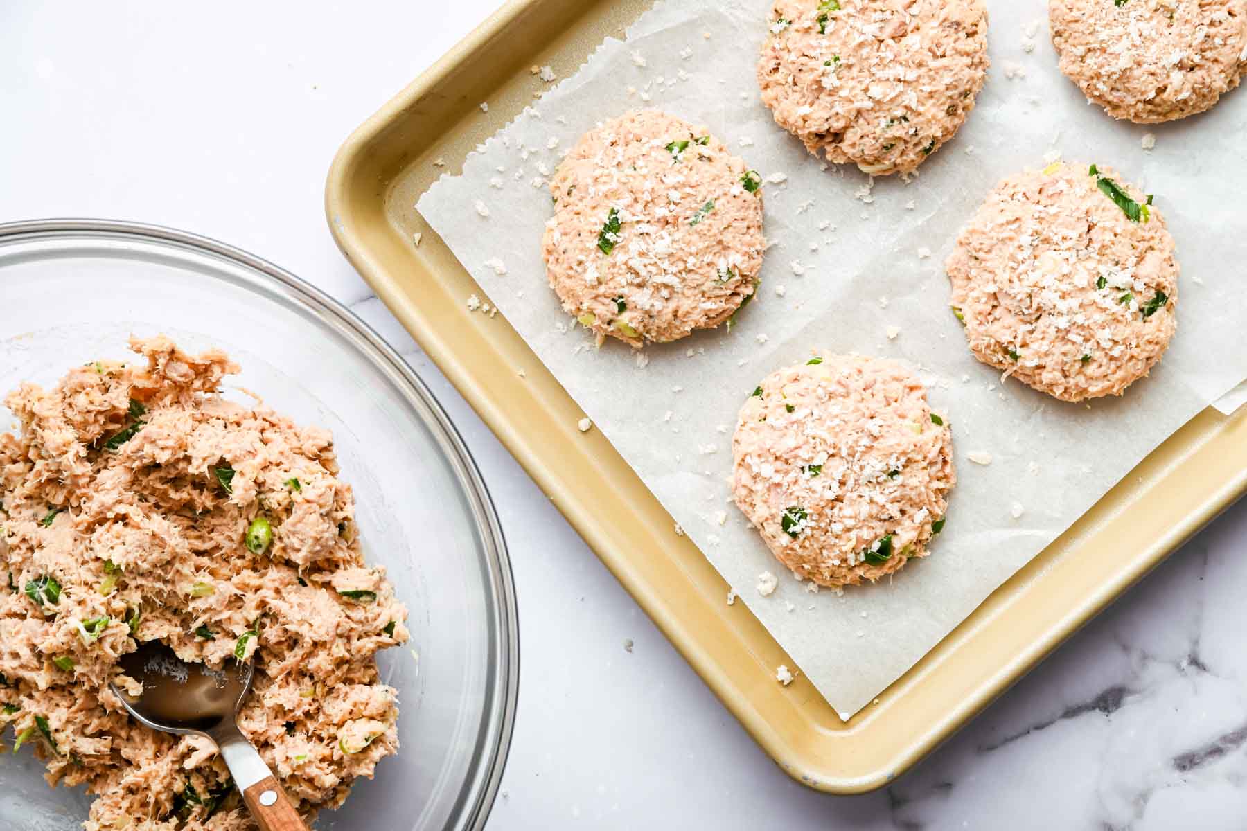 Tuna patties on a baking sheet, before being fried.