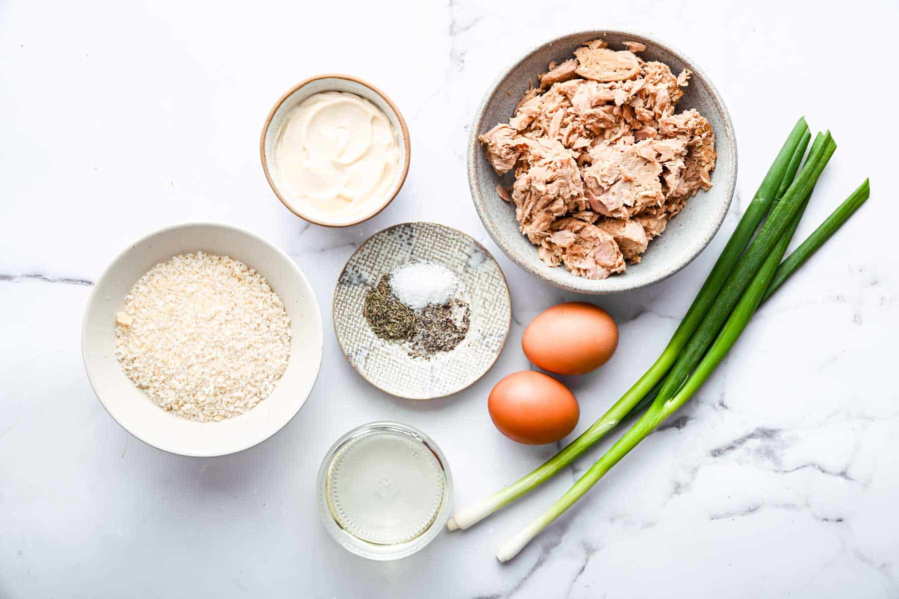Bowls of bread crumbs, spices, canned fish, and scallions on kitchen counter.