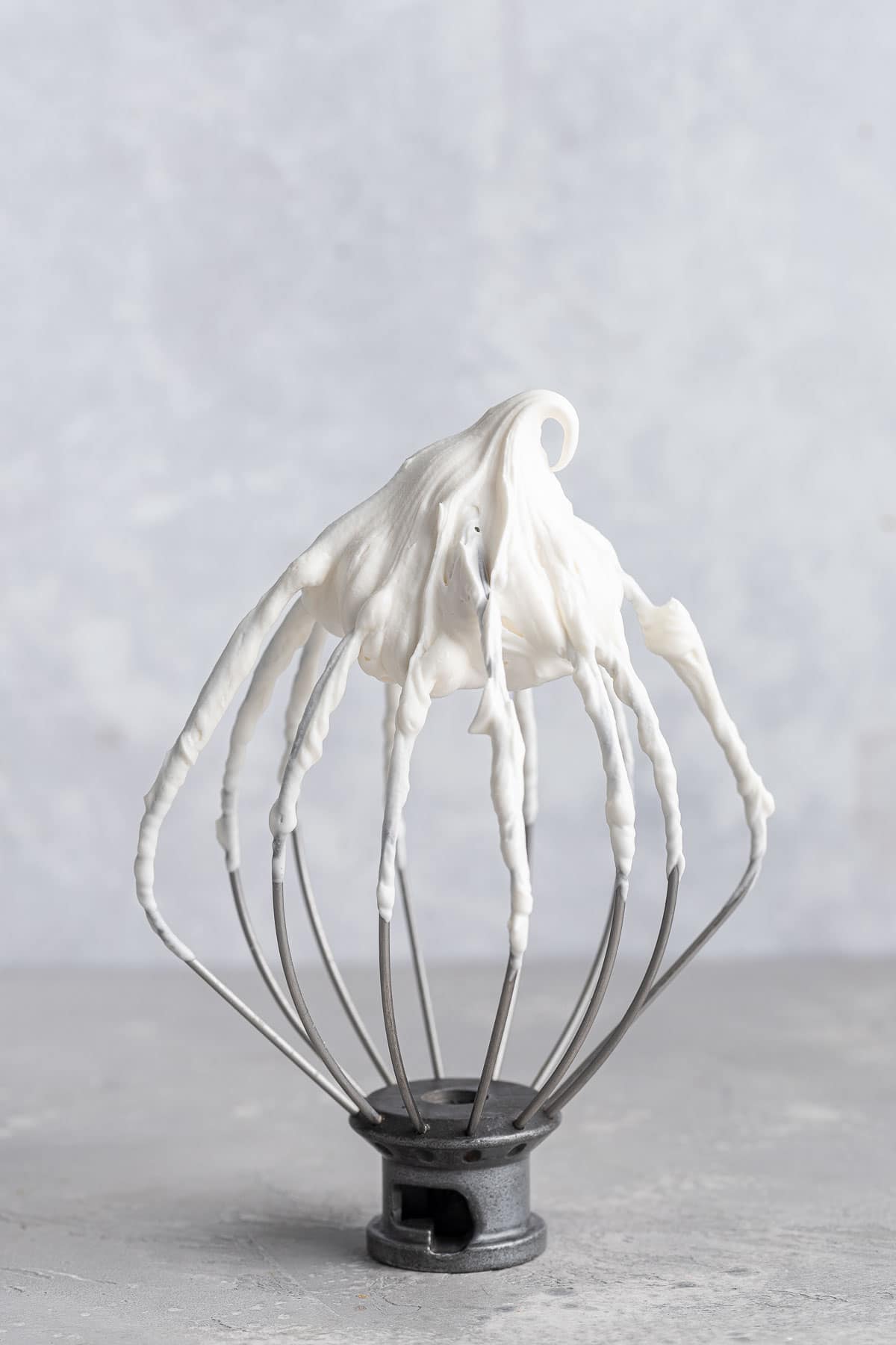 Stand mixer beater with white frosting on tip.