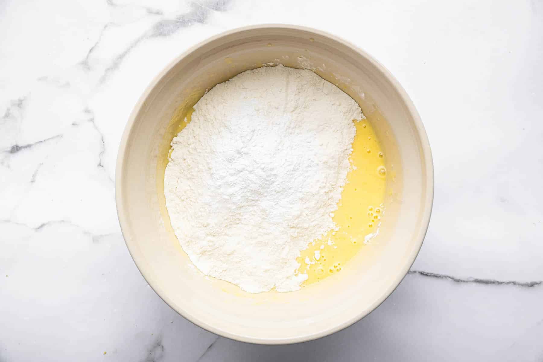 Bowl with yellow cake batter and white flour on top.