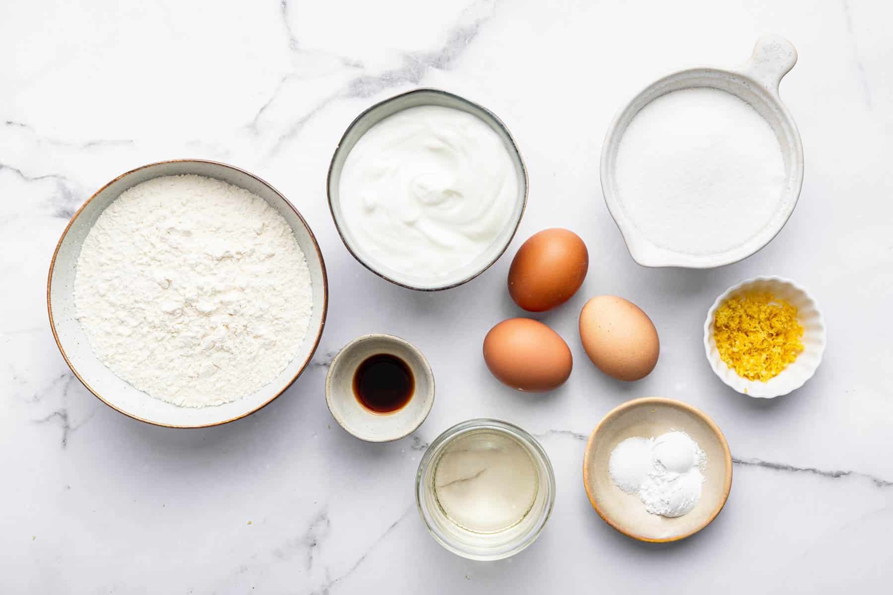 Round white bowls with flour, sugar, and 3 bowls on kitchen counter.