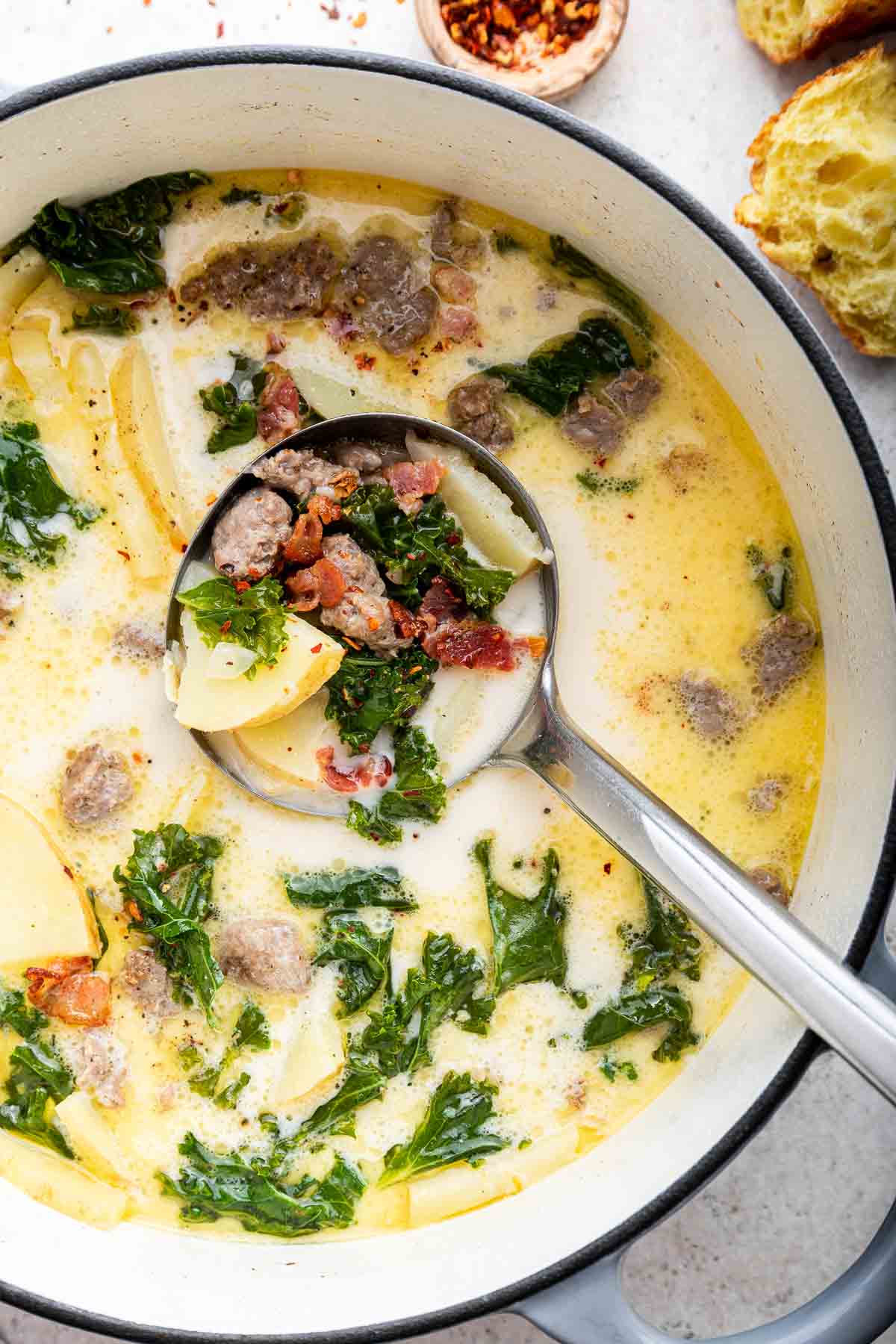 Overhead vertical shot of Zuppa Toscana with spoon removing a ladle-full.